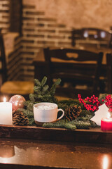 Christmas hot chocolate with mini marshmellows in an old ceramic mug with candles on a wooden background