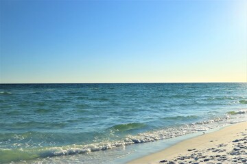 The seascape, a beautiful blank view from the coast of the Gulf of Mexico, calm ocean waters without waves over the horizon converge with a clear blue sky, in the foreground you can see the coast with