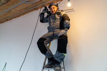 a worker climbed a ladder and sits holding a puncher as if it were a military weapon
