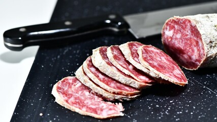 Slices of Italian artisanal Felino salami on a kitchen cutting board. Felino, Parma, Emilia Romagna / Italy