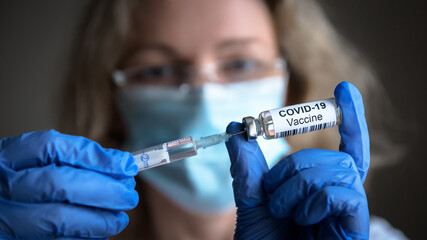 COVID-19 coronavirus vaccine, bottle and syringe in doctor hands