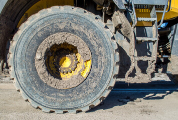 heavy duty  bulldozer tire and steps caked in mud on a sunny day