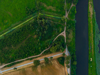 Aerial top down look to streets and paths between forest and fields and river on side