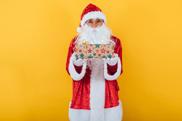 Fototapeta na wymiar Santa Claus hold a gift on yellow background. Christmas concept