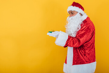 Santa Claus hold a gift on yellow background. Christmas concept