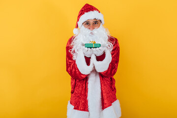 Fototapeta na wymiar Santa Claus hold a gift on yellow background. Christmas concept