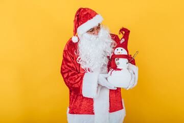 Fototapeta na wymiar Santa Claus holding a snowman on yellow background. Christmas concept