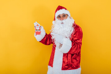 Santa Claus holding a small Santa Claus on yellow background. Christmas concept