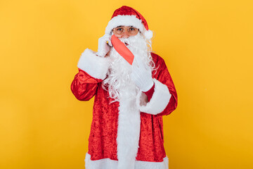 Fototapeta na wymiar Santa Claus putting on a red face mask, on yellow background. Christmas concept