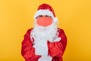 Portrait of Santa Claus wearing red face mask, on yellow background. Christmas concept