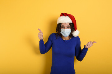 Fototapeta na wymiar Girl with christmas hat is optimistic about the defeat of covid 19 coronavirus. cyan background.