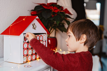 Little child opening first day in handmade advent calendar made from toilet paper rolls....