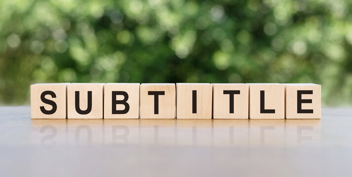 The subtitle is a word written on wooden blocks. The text is written in black letters and is reflected on the mirror surface of the table. Business concept for your design.