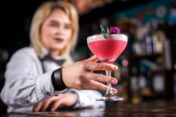 Girl barman creates a cocktail in the taproom