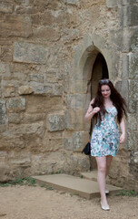 Fototapeta na wymiar Long haired brunette teenage girl walking through ancient stone archway