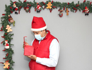 latin man with protection mask and gift box in christmas decoration, new normal covid-19