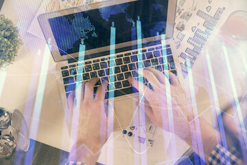 Fototapeta na wymiar Double exposure of man's hands typing over laptop keyboard and forex chart hologram drawing. Top view. Financial markets concept.