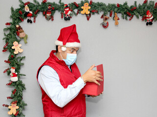 latin man with protection mask and gift box in christmas decoration, new normal covid-19