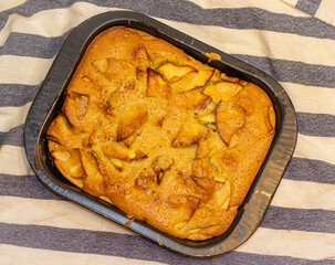 Apple charlotte in the cake tin on the striped tablecloth. 