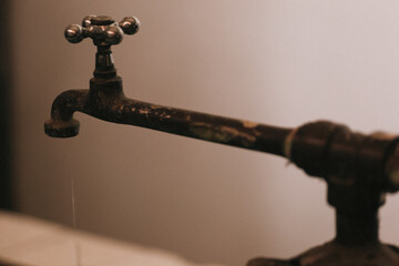 Old water tap with a little weak stream of water