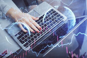 Double exposure of businesswoman hands typing on computer and financial graph hologram drawing. Stock market analysis concept.