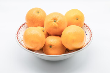 Orange fruits on a porcelain source isolated on a white background