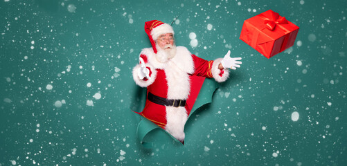 Portrait of Santa Claus with a red gift on a green studio background.