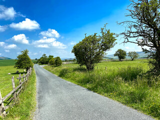 View along, Brackenley Lane, with fields, trees, and hills in the far distance near, Skipton, Yorkshire, UK