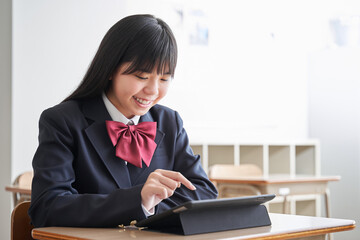 教室でタブレットを操作する日本人女子中学生 © mapo