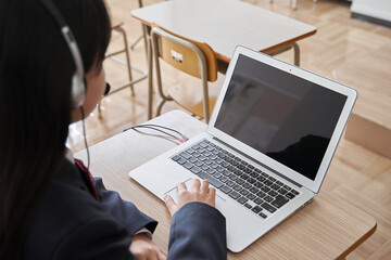 教室でパソコンで授業を受ける日本人女子中学生