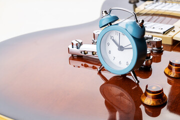 old vintage blue clock stands on an electric guitar. music time concept. time to relax conceptual