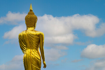 Obraz premium Golden buddha statue standing with the blue sky