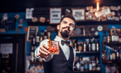 Young barman adds ingredients to a cocktail at the night club
