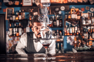 Bearded bartender pouring fresh alcoholic drink into the glasses on the bar