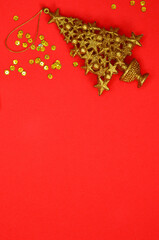 golden christmas decoration and gold confetti copy space on red background, xmas theme top view flat lay
