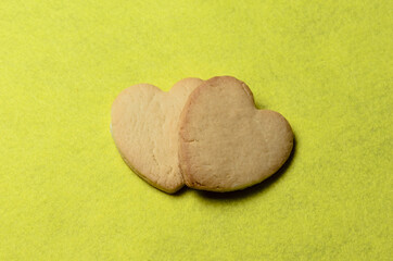 Homemade cookies with a beautiful texture of a crust baked in a heart shape on a yellow background.