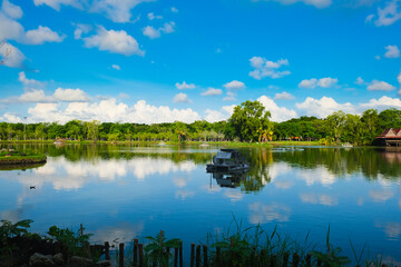 Obraz na płótnie Canvas Green tree park meadow pool against blue sky with cloud