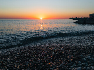 Obraz premium Beautiful sunset on the beach Scene with waves by the sea with the reflection of sun rays on the water and the sun on the horizon. Calm and relaxing seascape view.