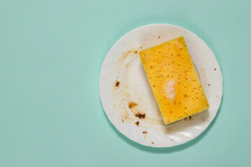 Dirty white plate and sponge with cleaning gel on a blue background.