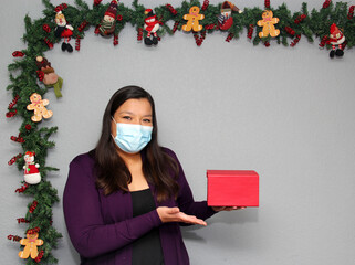 black hair latin woman with protection mask and gift box in christmas decoration, new normal...