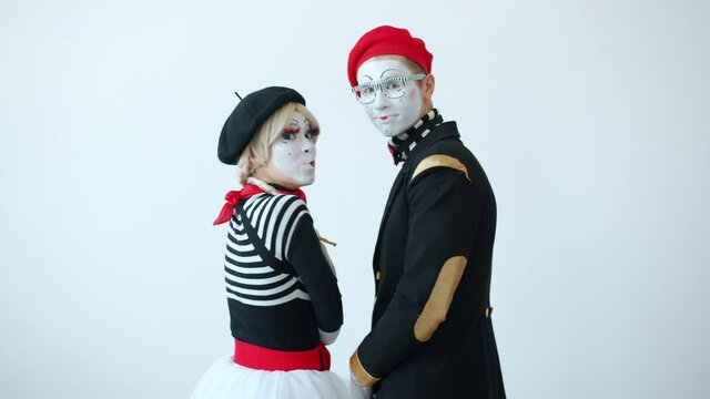 Back view of couple of mimes cheerful girl and guy turning to camera smiling and looking with happy faces. Positive emotions and people concept.