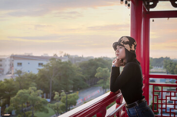Portrait of Asian young woman relaxing on the viewpoint with breathtaking view over city at the terrace with peaceful nature scenery, looking at sunset or sunrise on horizon, copy space for text.