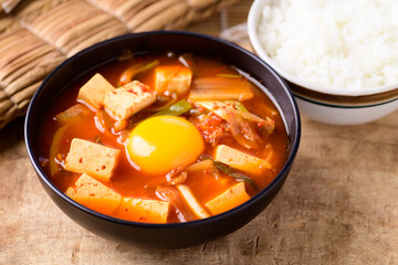 Korean food, Kimchi soup with tofu and egg eating with cooked rice on wooden background