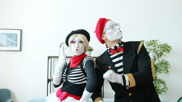 Young man and woman mimes are enjoying dances and music indoors in apartment moving bodies dancing having fun. Leisure time and happiness concept.
