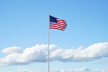 waving USA flag on pole against blue sky