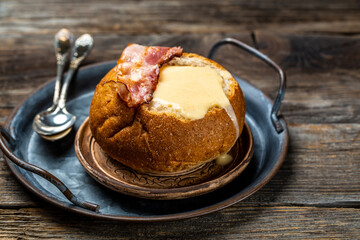 Cream soup of potatoes, vegetables, cheese, fried bacon in bread, cheese soup served with spoon....