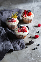 Homemade muffin next to a bottle of milk on a table and on a dark background with fresh berries around