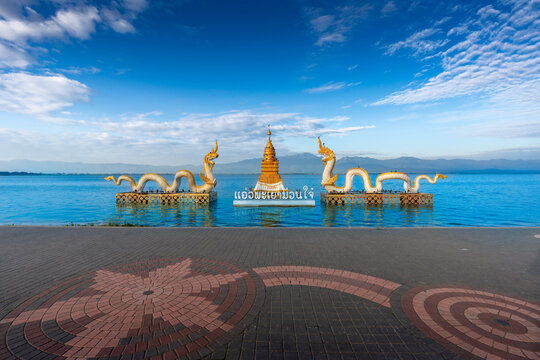 Naga statue with bright sky, clouds, mountains background and fresh water lake (Kwan Phayao, one of Phayao famous attractions.) in Phayao, Thailand (Thai Language translate &ldquo;Happiness Phayao&rdquo; ).