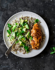Quinoa with baked chicken and avocado salad on dark background, top view. Healthy food concept