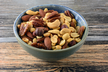 Fototapeta na wymiar Mixed nuts with peanuts, almonds, cashews, hazelnuts and pecans in snack bowl on table